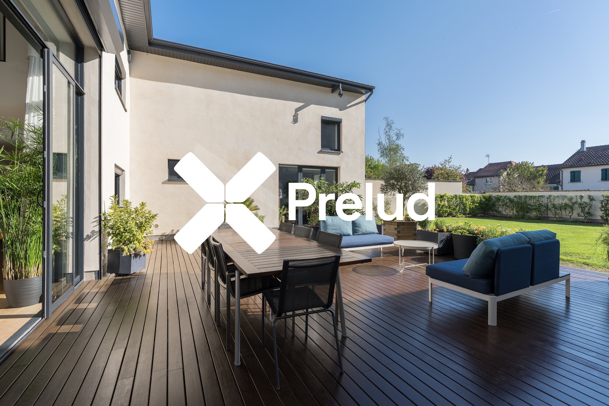 Terrasse en bois avec salon lounge, table repas et jardin aménagé